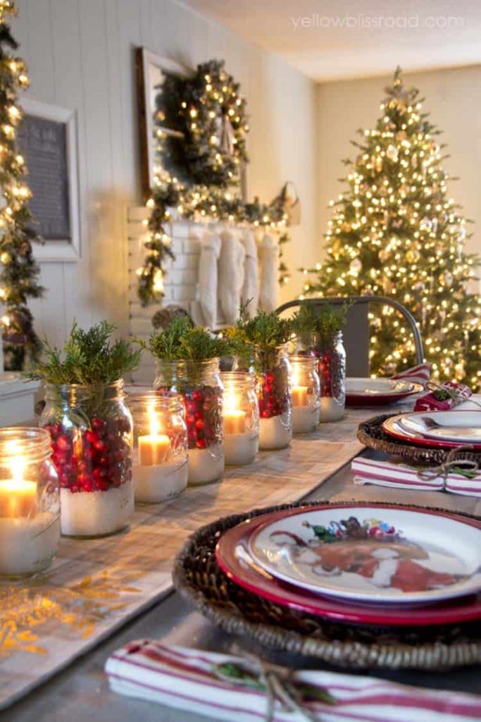 Candles on a table with christmas tree and stockings in the background